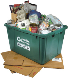 Photo of full green recycling bin sitting on folded up cardboard